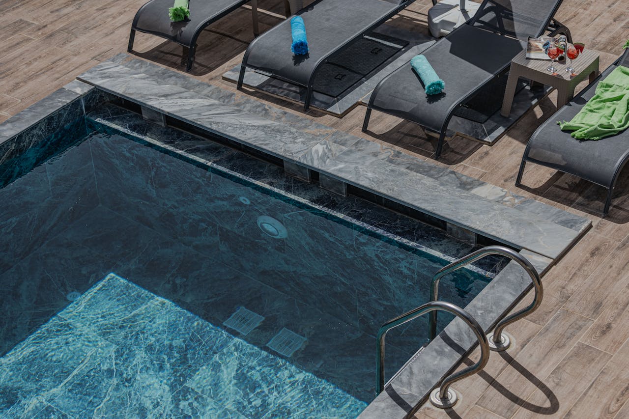 Luxury swimming pool with stone deck and modern lounge chairs