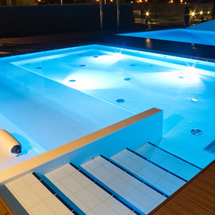 Modern spa pool with underwater lighting, steps, and tiled seating area
